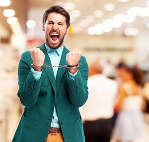 hombre nervioso gritando con esposas en las muñecas