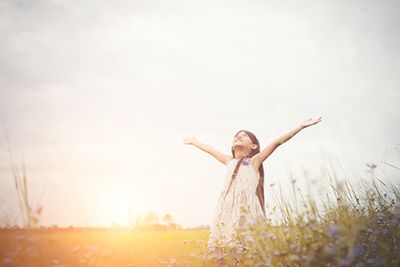 Pequeña niña al sol en un campo de flores. Libertad disfrutando con la naturaleza