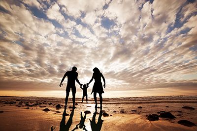 Familia feliz, juntos de la mano en la playa al atardecer, tiempo de verano. Madre, padre y un niño pequeño
