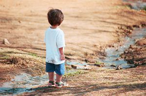 Niño de espaldas observando un pequeño arroyo