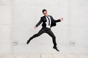 hombre de negocios joven congafas saltando en la calle